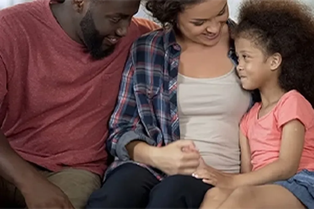Parents and child smiling together on a sofa